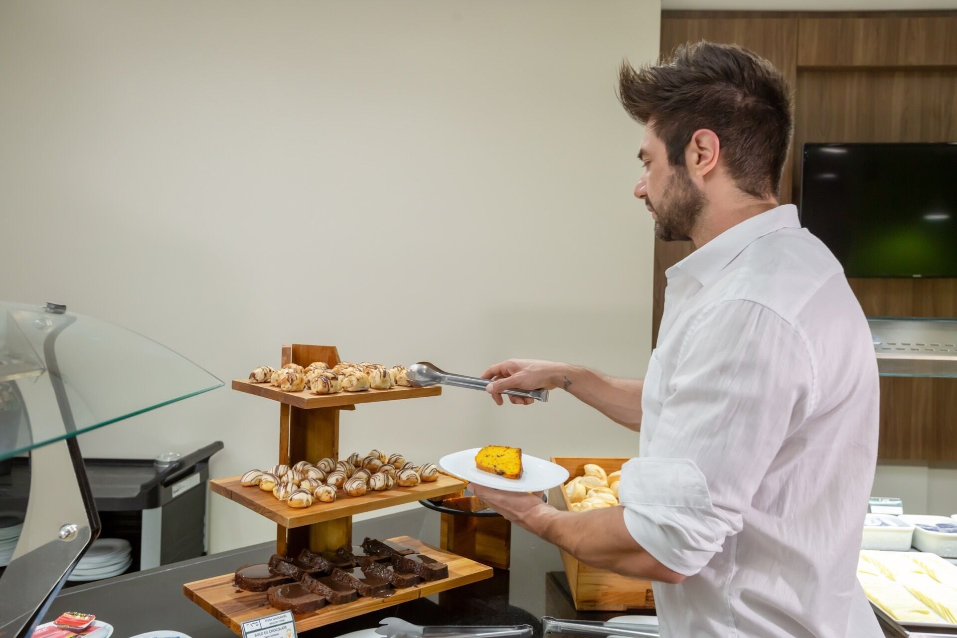 Een buffetopstelling met diverse desserts en iemand die eten serveert.