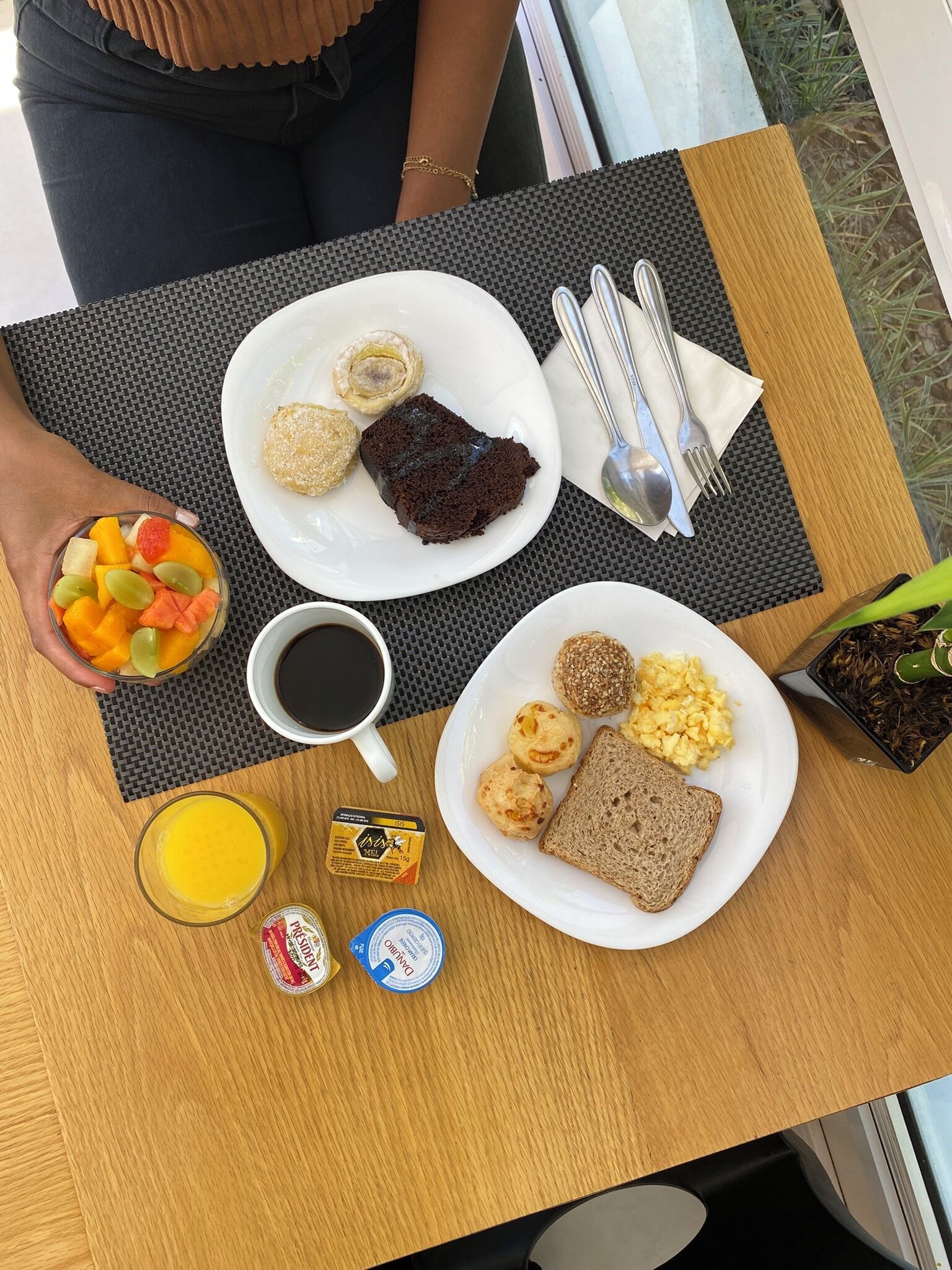 Una mesa de desayuno con platos de comida, una taza de café y un vaso de jugo de naranja.