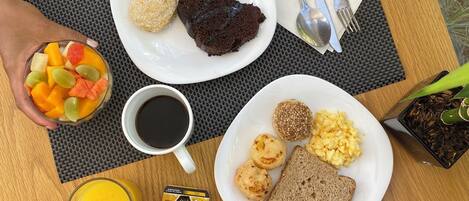 Una mesa de desayuno con platos de comida, una taza de café y un vaso de jugo de naranja.