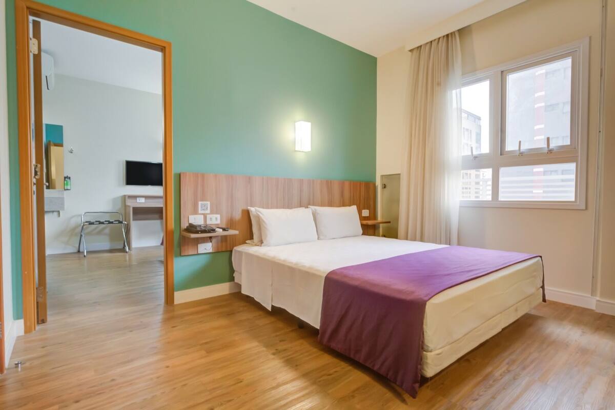 Une chambre d’hôtel avec un lit, un bureau et une chaise.