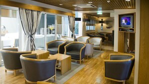 Un moderno hall de hotel con asientos cómodos, un televisor y vistas al exterior.
