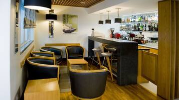 A bar area with wooden furniture, a counter with bottles, and a wall-mounted lamp.