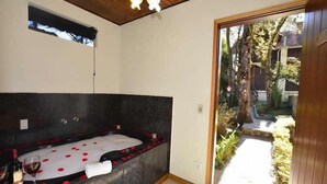 Une salle de bain avec une grande baignoire, une petite fenêtre et une vue sur un jardin.