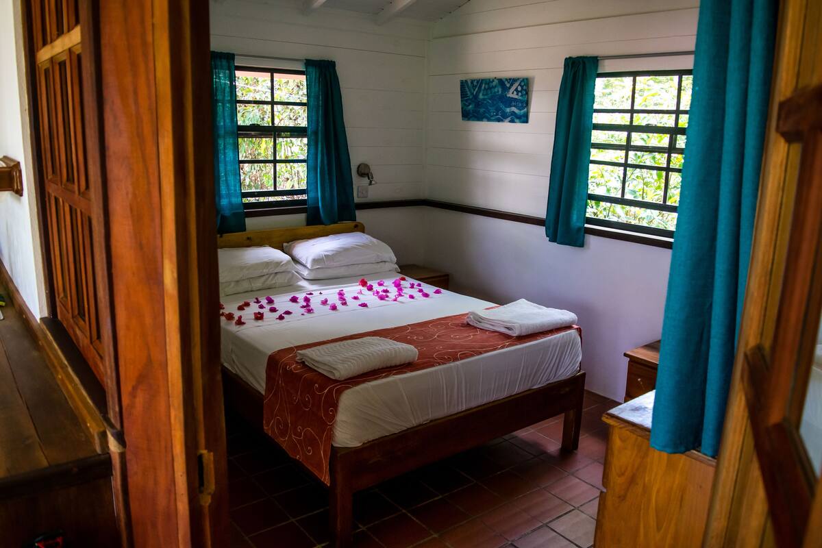 A bedroom with a wooden bed, white linens, and teal curtains.