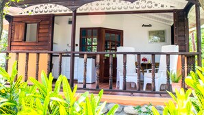 A wooden house with a porch, a dining area, and a kitchen visible through the open door. - Bogles Round House (Hillsborough)