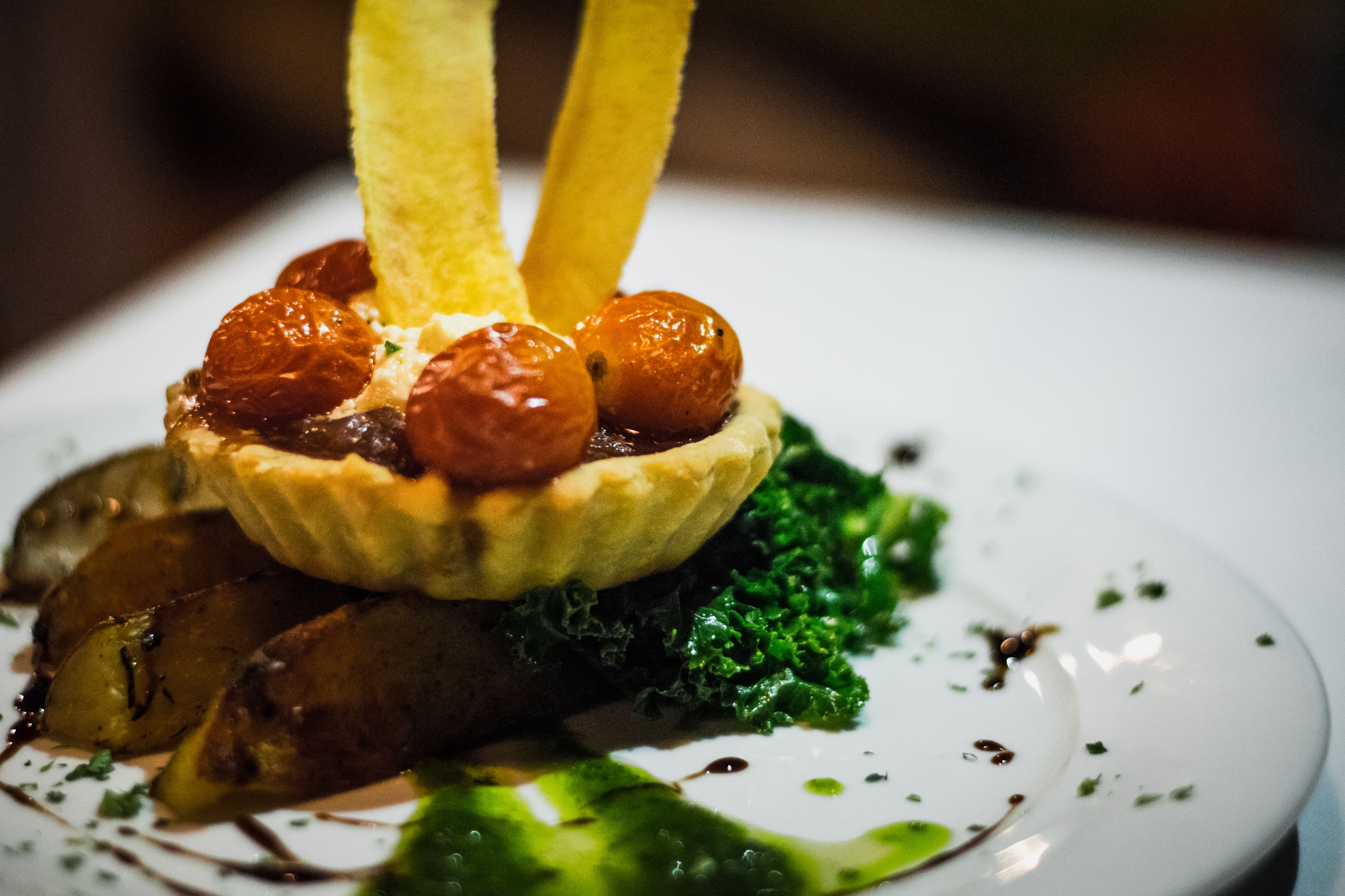 Une assiette de dessert avec une tarte, des pommes de terre rôties et des légumes verts.