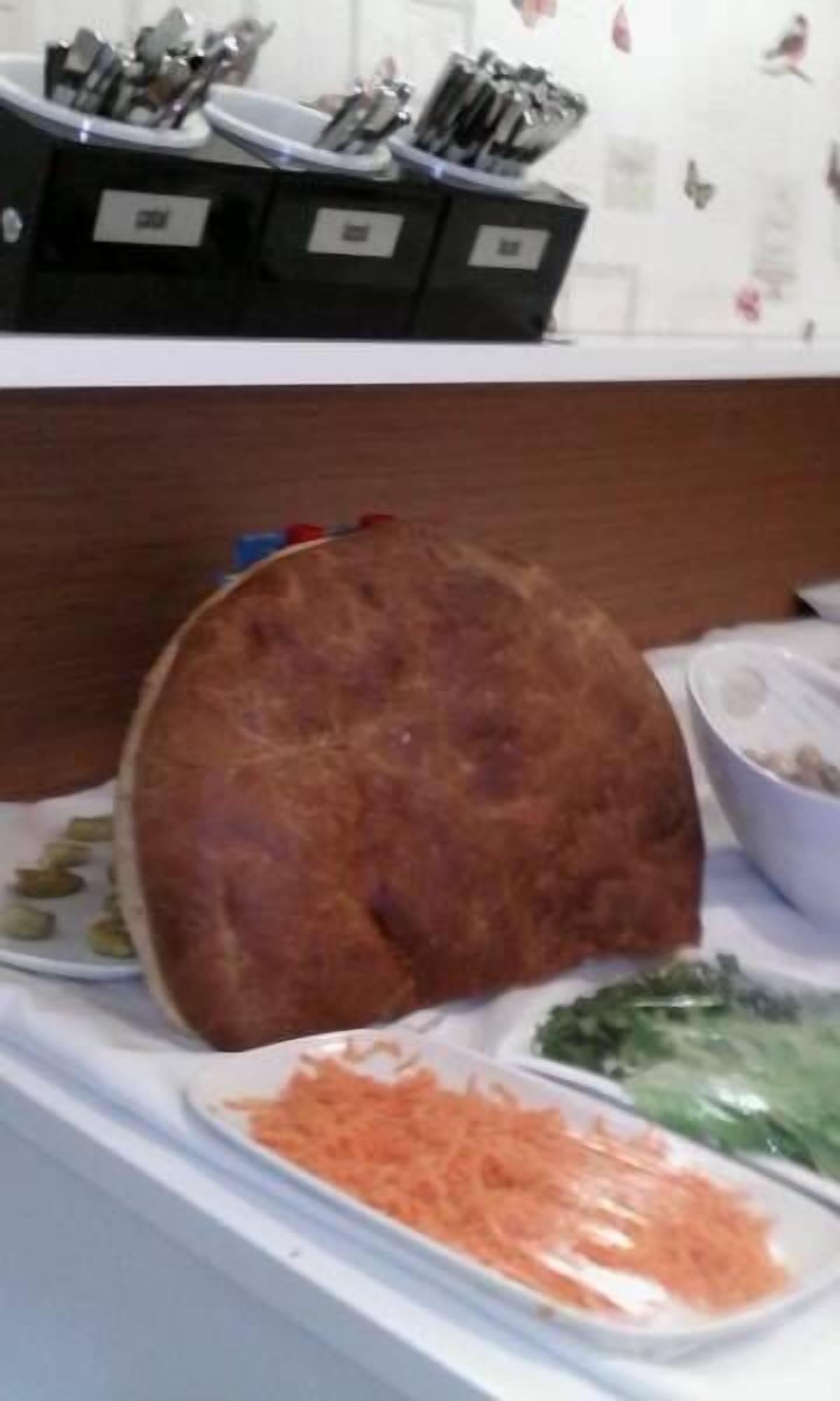 Un plan de travail de cuisine avec un pain, un bol de carottes râpées et une assiette de légumes verts.