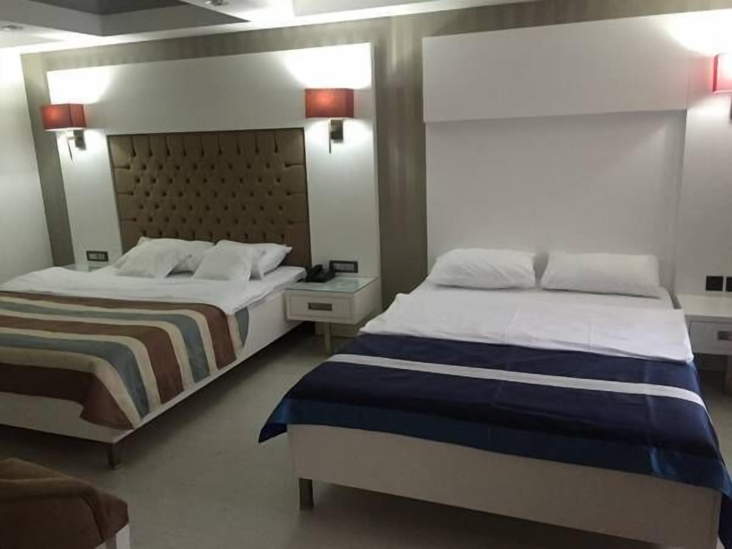 Habitación de hotel con dos camas, cada una con cabecero y mesitas de noche.