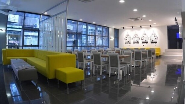 Eine moderne Hotelhalle mit einem gelben Sofa, einem Essbereich und großen Fenstern.