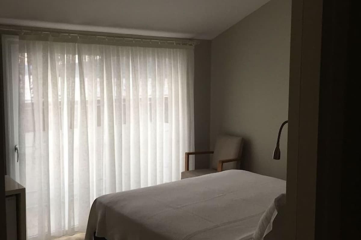 A bedroom with a bed, a chair, and a desk.