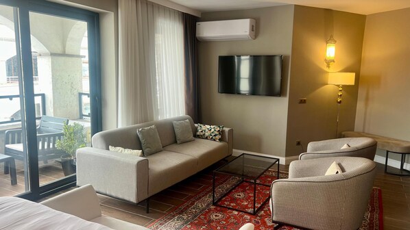 Una sala de estar moderna con un sofá, sillones, un televisor y una lámpara.