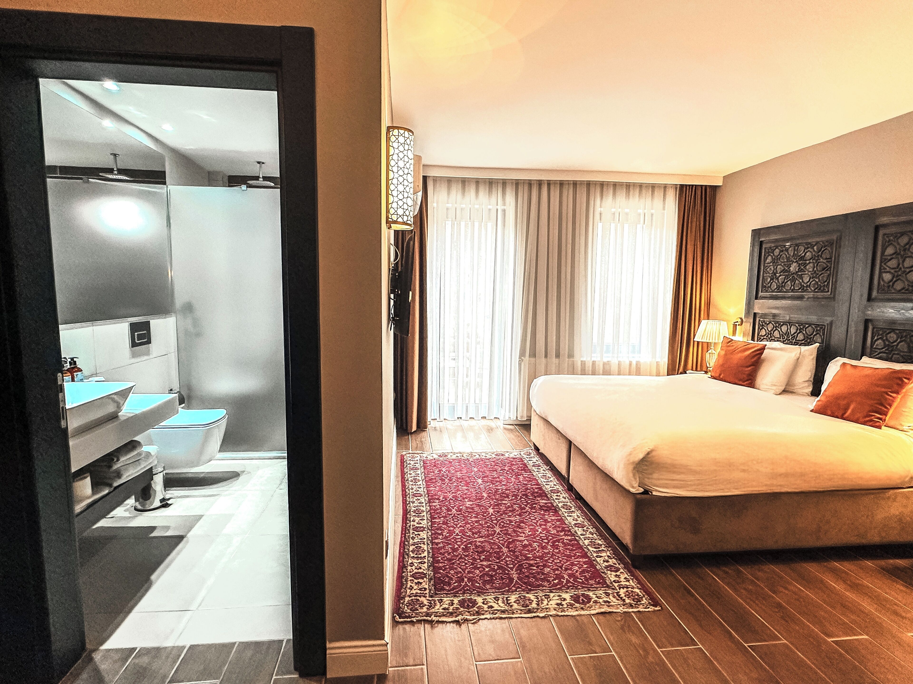 Una camera d'albergo con un letto, un bagno e vista sulla città.