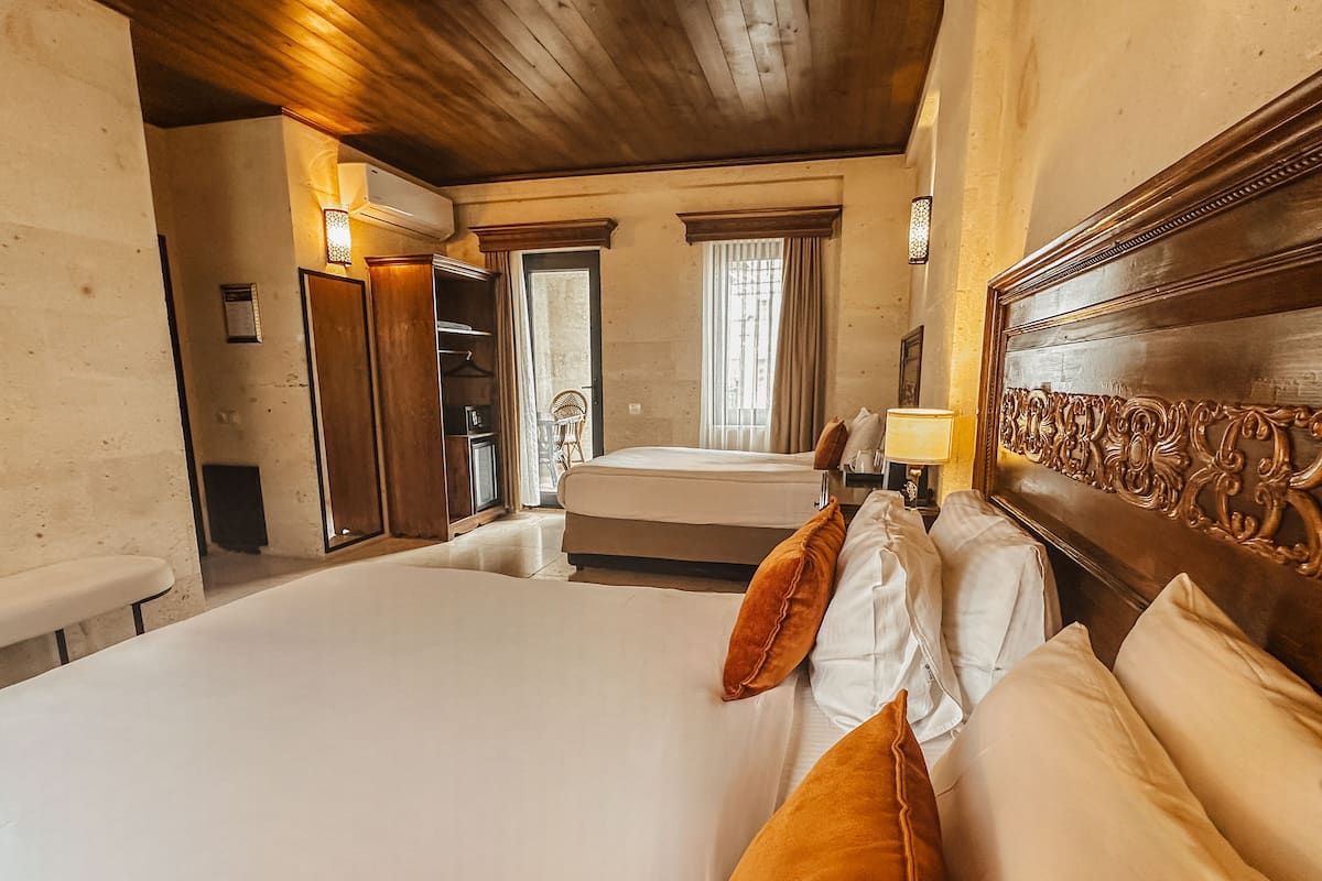A hotel room with a large bed, wooden headboard, and a small table with a lamp.