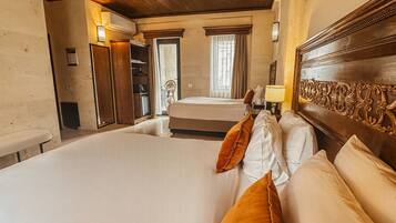 A hotel room with a large bed, wooden headboard, and a small table with a lamp.