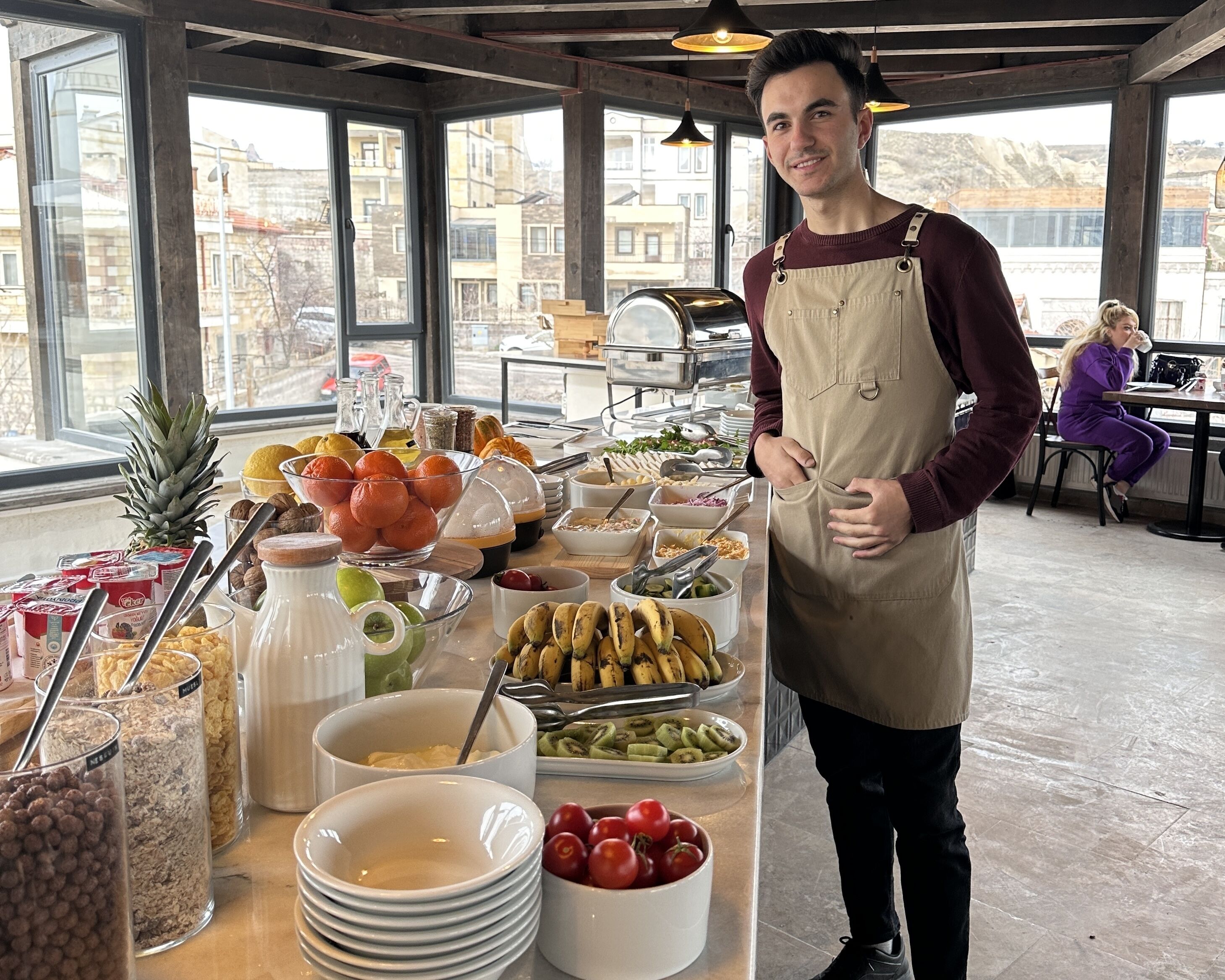 Buffet montado com diversos alimentos e uma pessoa perto do balcão.