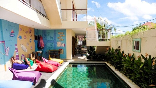 Zona de piscina con sillones inflables de colores y un mural en la pared.