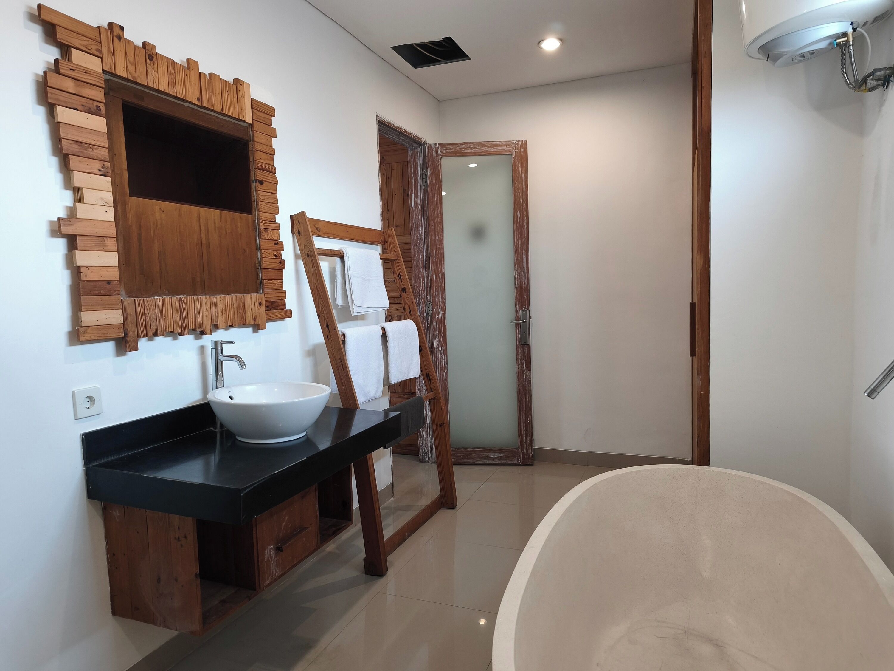 A bathroom with a wooden vanity, a large sink, and a bathtub.