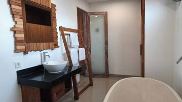 A bathroom with a wooden vanity, a large sink, and a bathtub.