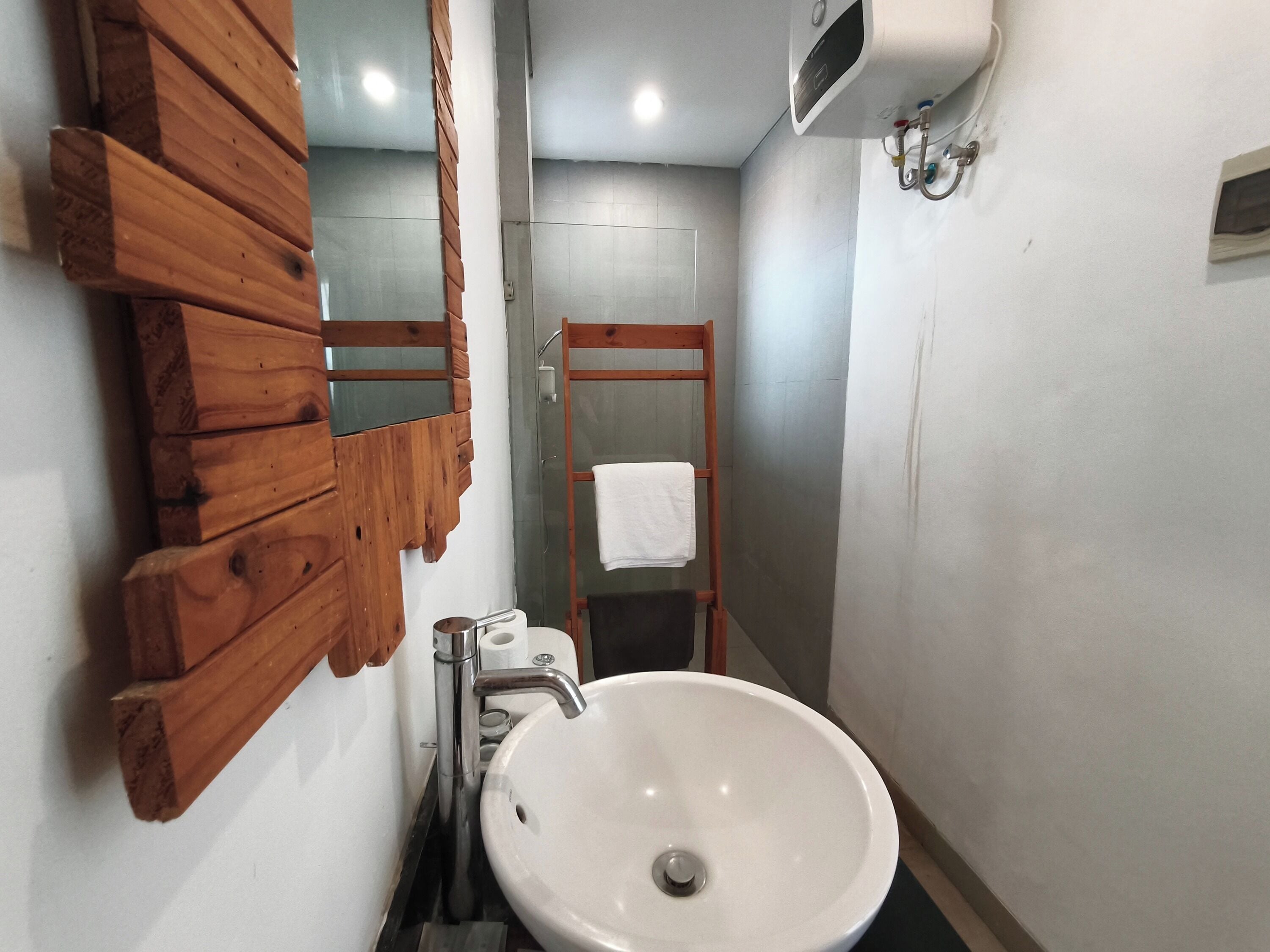 A bathroom with a wooden vanity, a white sink, a towel rack, and a glass shower enclosure.
