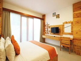 Una habitación de hotel con una cama, un escritorio, un televisor y una ventana con cortinas.