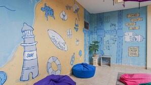 Una habitación temática de playa con un mural, pufs y una mesita con una planta.