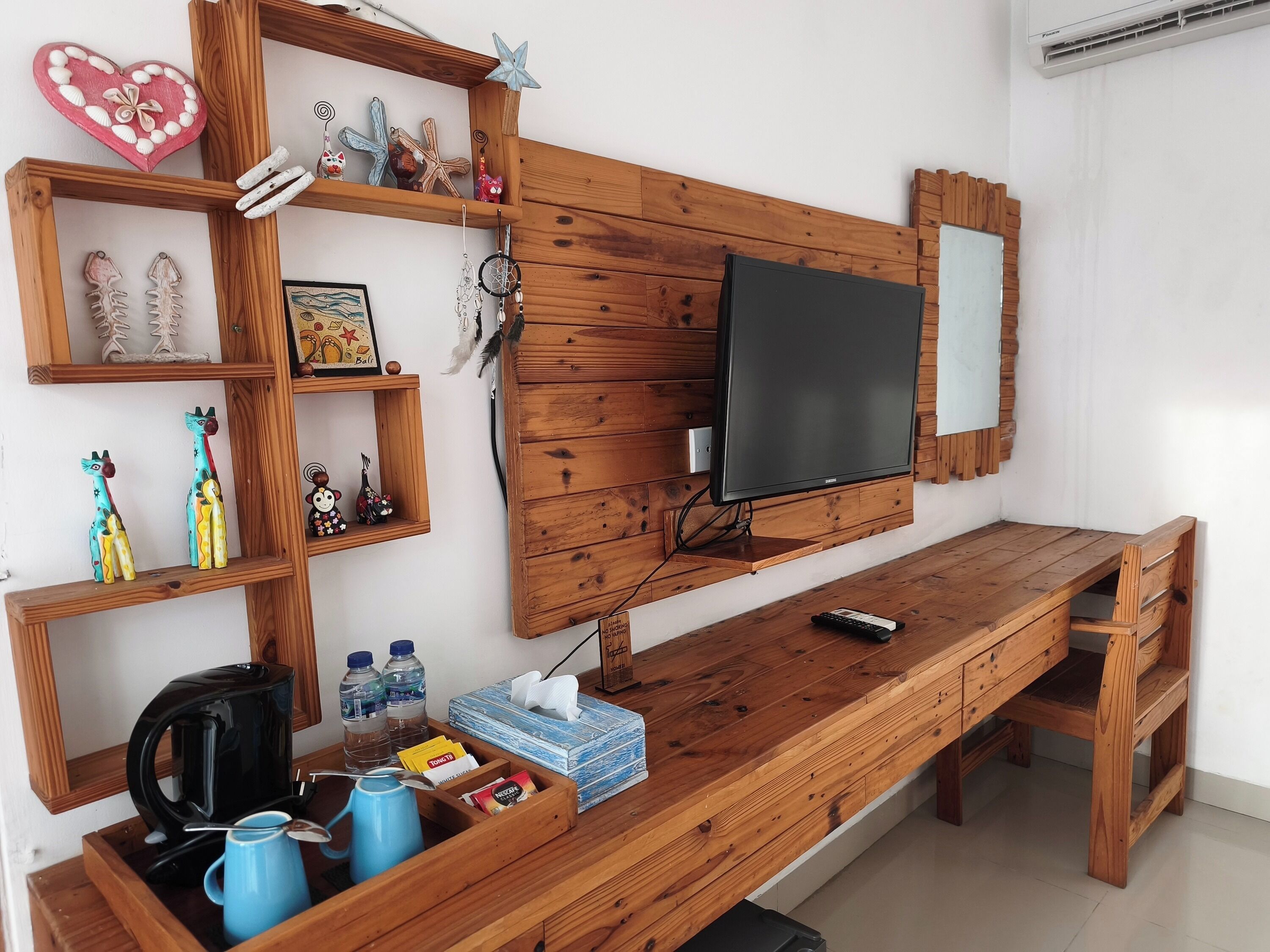A wooden TV stand with a flat-screen TV, shelves with decorative items, a coffee maker, and a tissue box.