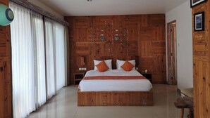 Un dormitorio espacioso con una cama grande de madera, ropa de cama blanca y un cabecero de madera.