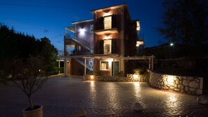 Un edificio de varios pisos con fachada de piedra, una escalera que conduce al nivel superior y una entrada bien iluminada.