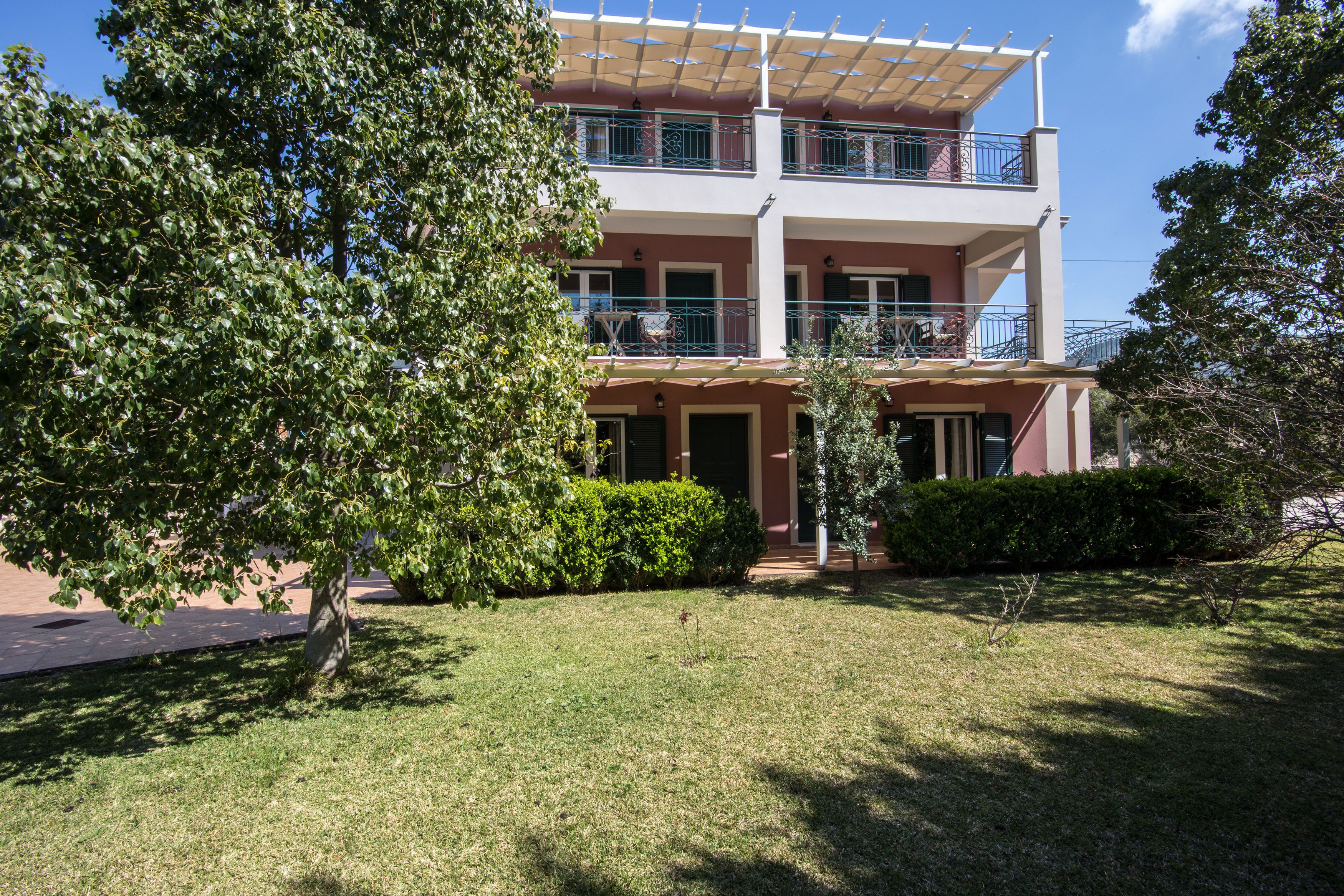 A two-story building with balconies, a covered patio, and a well-maintained lawn.