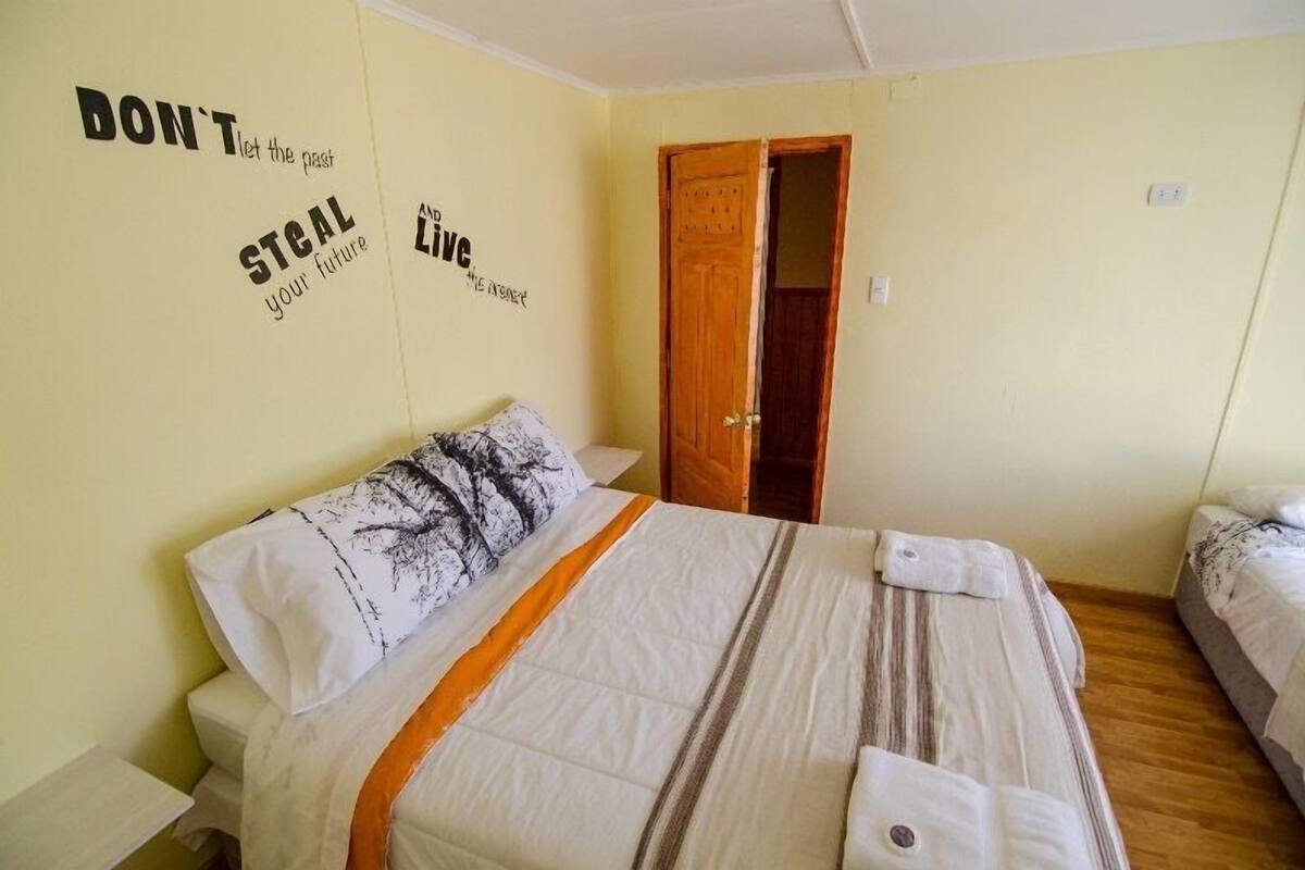 A bedroom with a bed, a nightstand, a door, and motivational wall art.