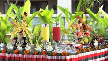 A table set with various drinks, a floral centerpiece, and a tropical backdrop.