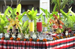 A table set with various drinks, a floral centerpiece, and a tropical backdrop.