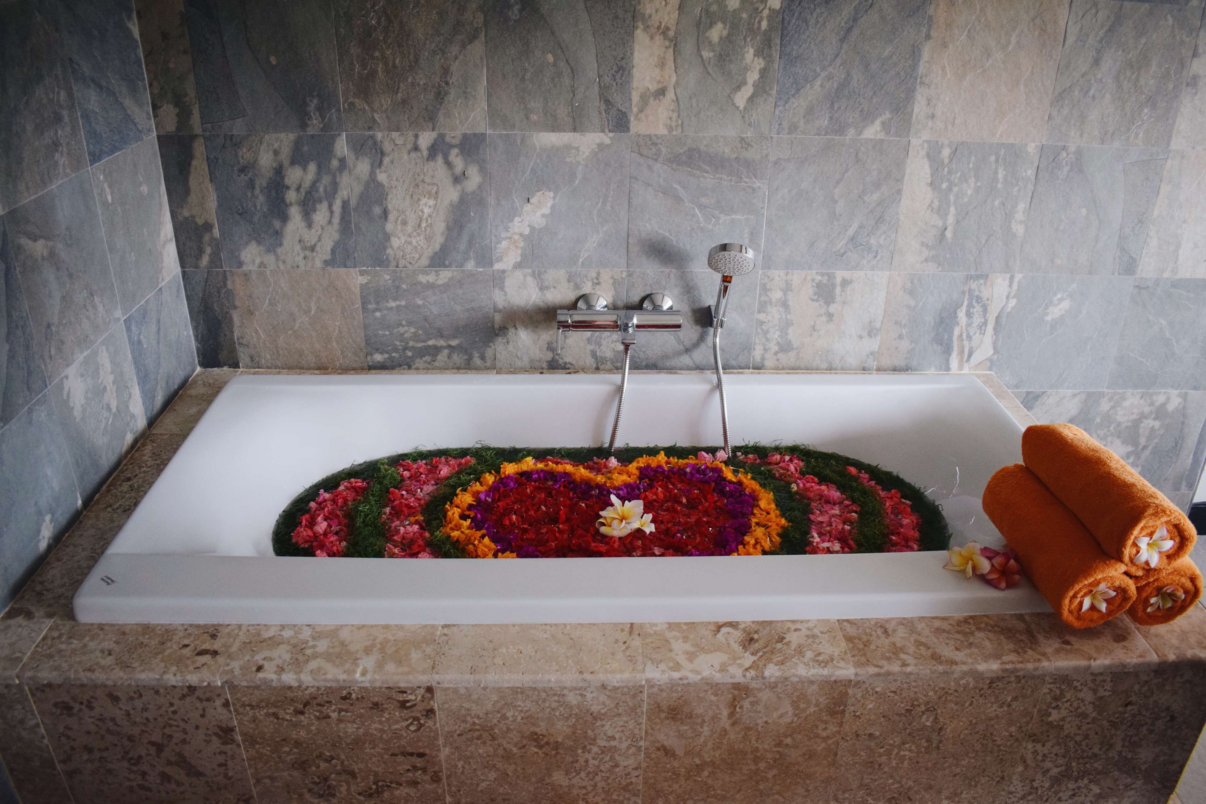 A bathtub with a floral arrangement and towels.