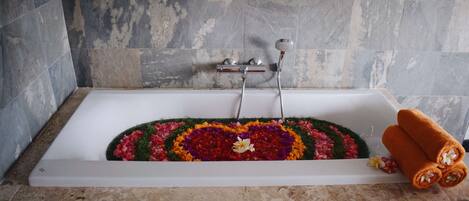 A bathtub with a floral arrangement and towels.