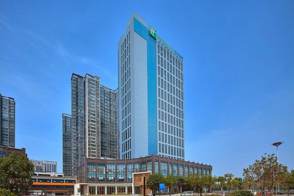 A high-rise hotel with a prominent blue and white facade, multiple floors, and a distinctive green logo at the top. - Holiday Inn Express Luoyang Yichuan by IHG (Luoyang)
