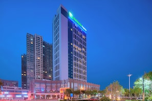A high-rise hotel with a prominent 'Hotel Express' sign, surrounded by other buildings and a well-lit urban environment. - Holiday Inn Express Luoyang Yichuan by IHG (Luoyang)