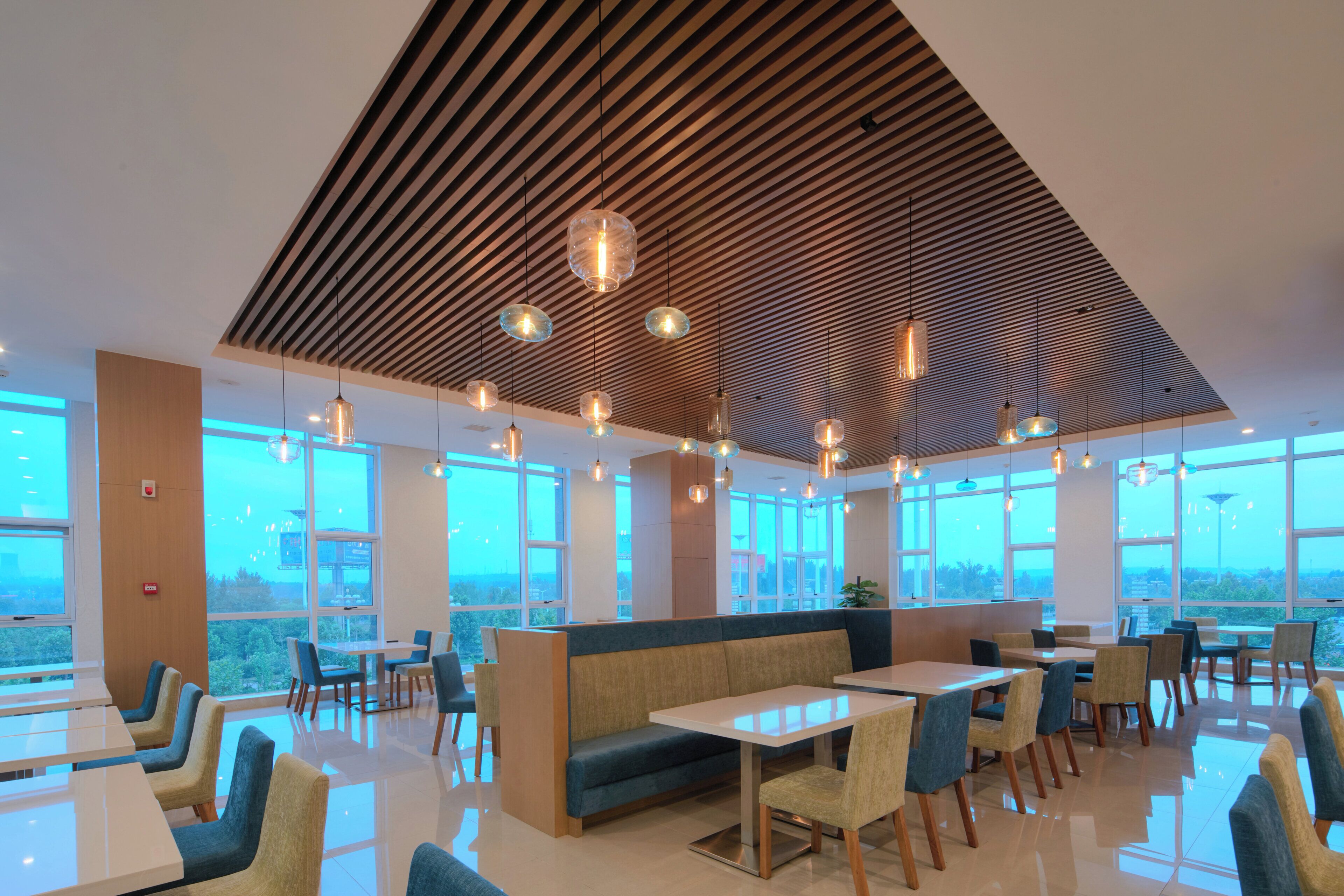 A modern restaurant with high ceilings, large windows, and a variety of seating options including tables and booths.