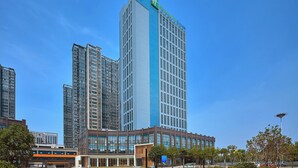 Um hotel alto com uma placa grande 'Holiday Inn Express', rodeado por outros edifícios e um céu azul claro.