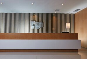 A reception desk with a modern design, featuring a wooden panel and a white counter. - Holiday Inn Express Luoyang Yichuan by IHG (Luoyang)
