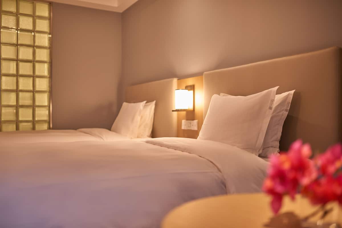 Ein Hotelzimmer mit einem großen Bett, einem Nachttisch mit Lampe und einem Fenster mit Blick.