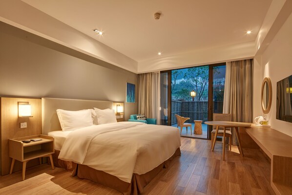 A modern hotel room with a large bed, bedside tables, a desk, and a balcony with a view of the city. - Holiday Inn Express - Zhejiang Qianxia Lake by IHG (Lishui)