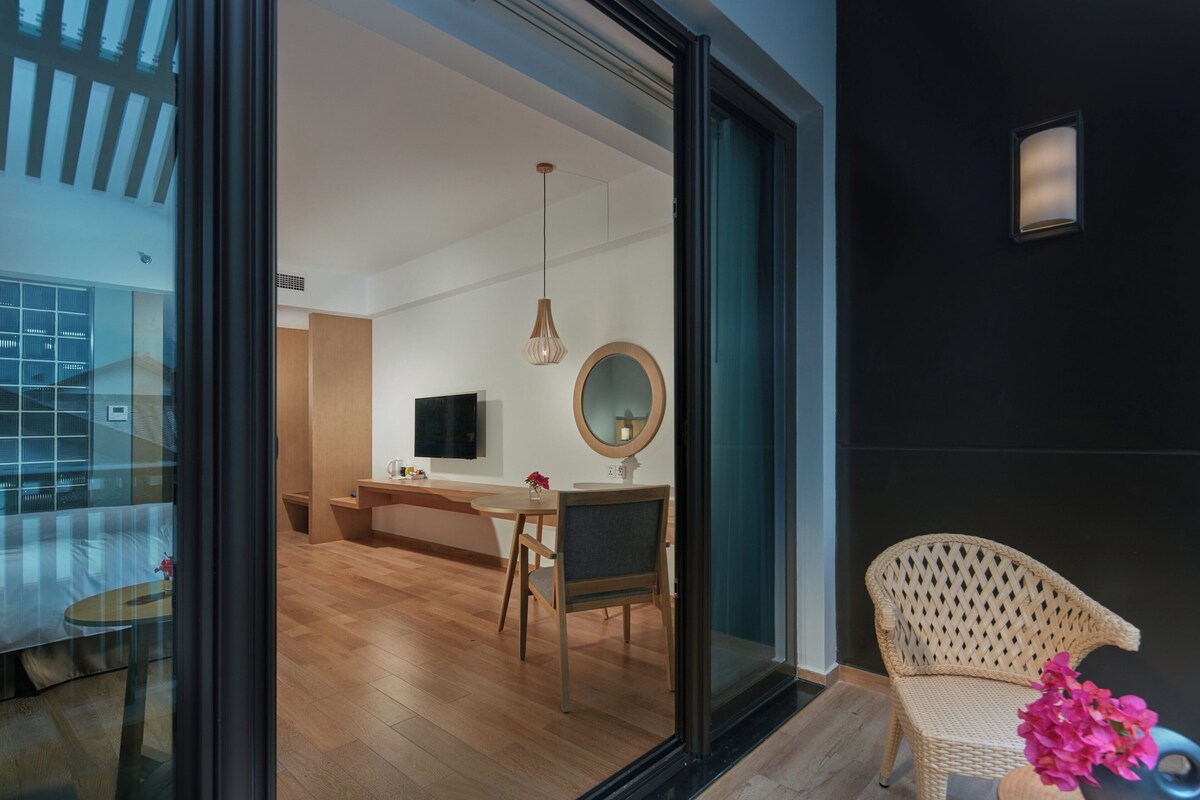 A modern interior with a dining area, a large mirror, and a wicker chair.