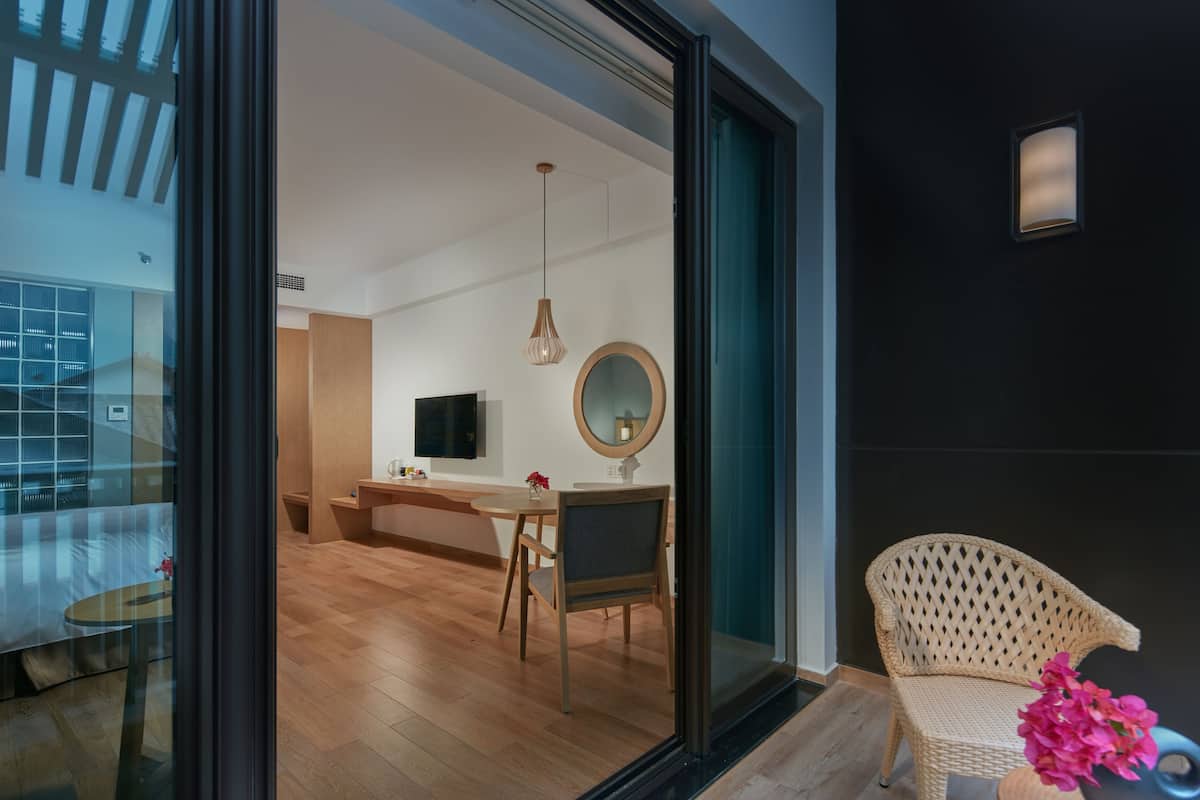 Ein modernes Interieur mit Essbereich, einem Korbstuhl und einer Glastür zu einem weiteren Raum.