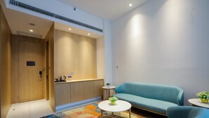 Une chambre d’hôtel moderne, dotée d’un canapé, d’une petite table basse et d’un tapis aux motifs géométriques et aux couleurs vives.