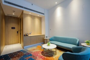 A modern hotel room with a sofa, a small coffee table, and a colorful geometric carpet.