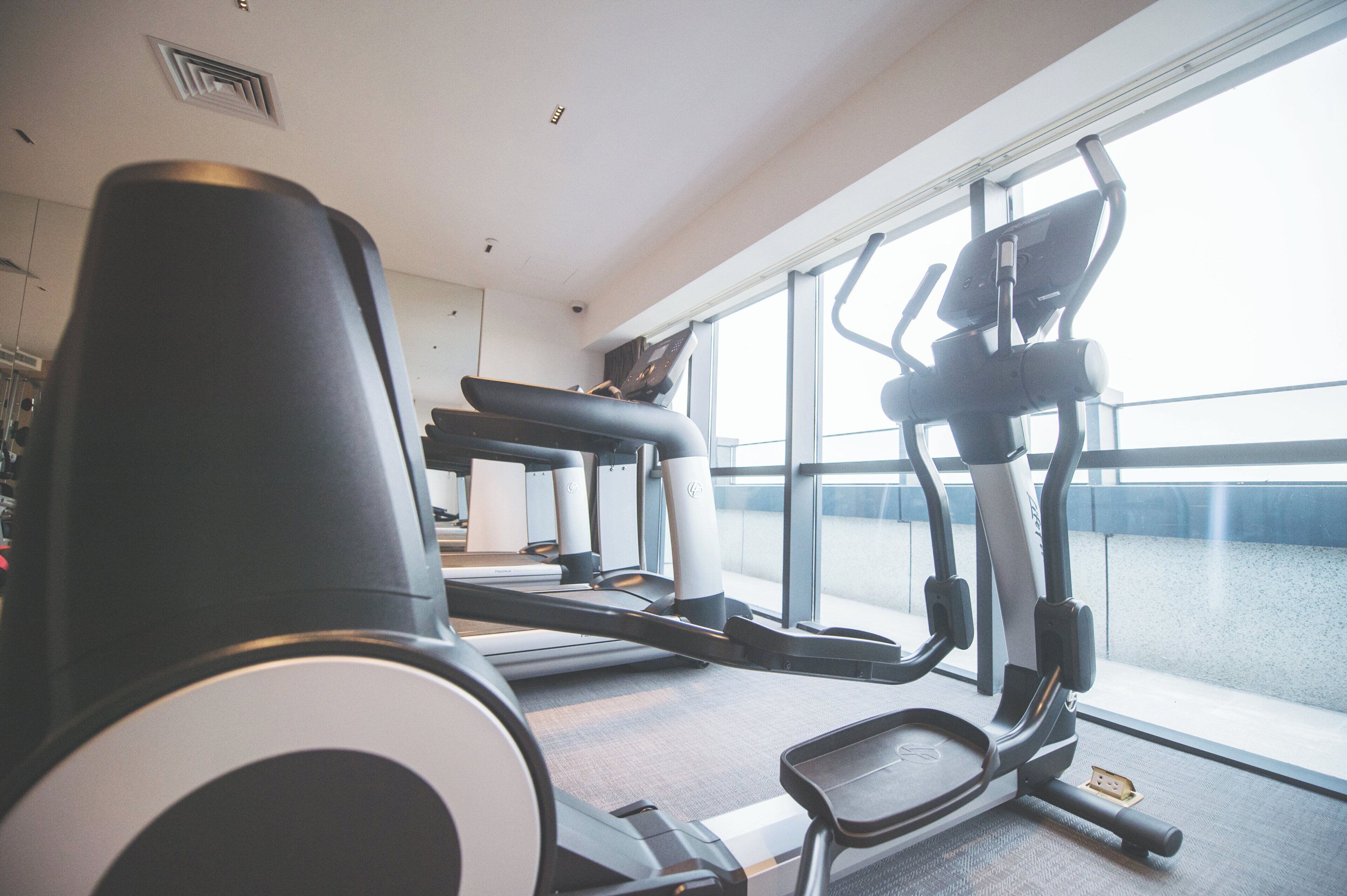 A gym with exercise equipment, a window with a view, and a ceiling vent.