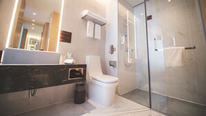 Une salle de bain moderne avec une douche à parois de verre, des toilettes blanches et un meuble-lavabo en marbre.