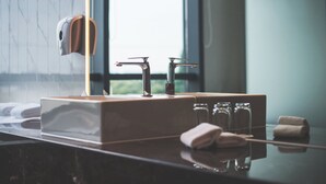 Une salle de bain moderne avec un comptoir en marbre, un distributeur de serviettes et un distributeur de savon en verre.