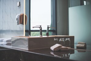 A modern bathroom with a marble countertop, a towel dispenser, and a glass soap dispenser.