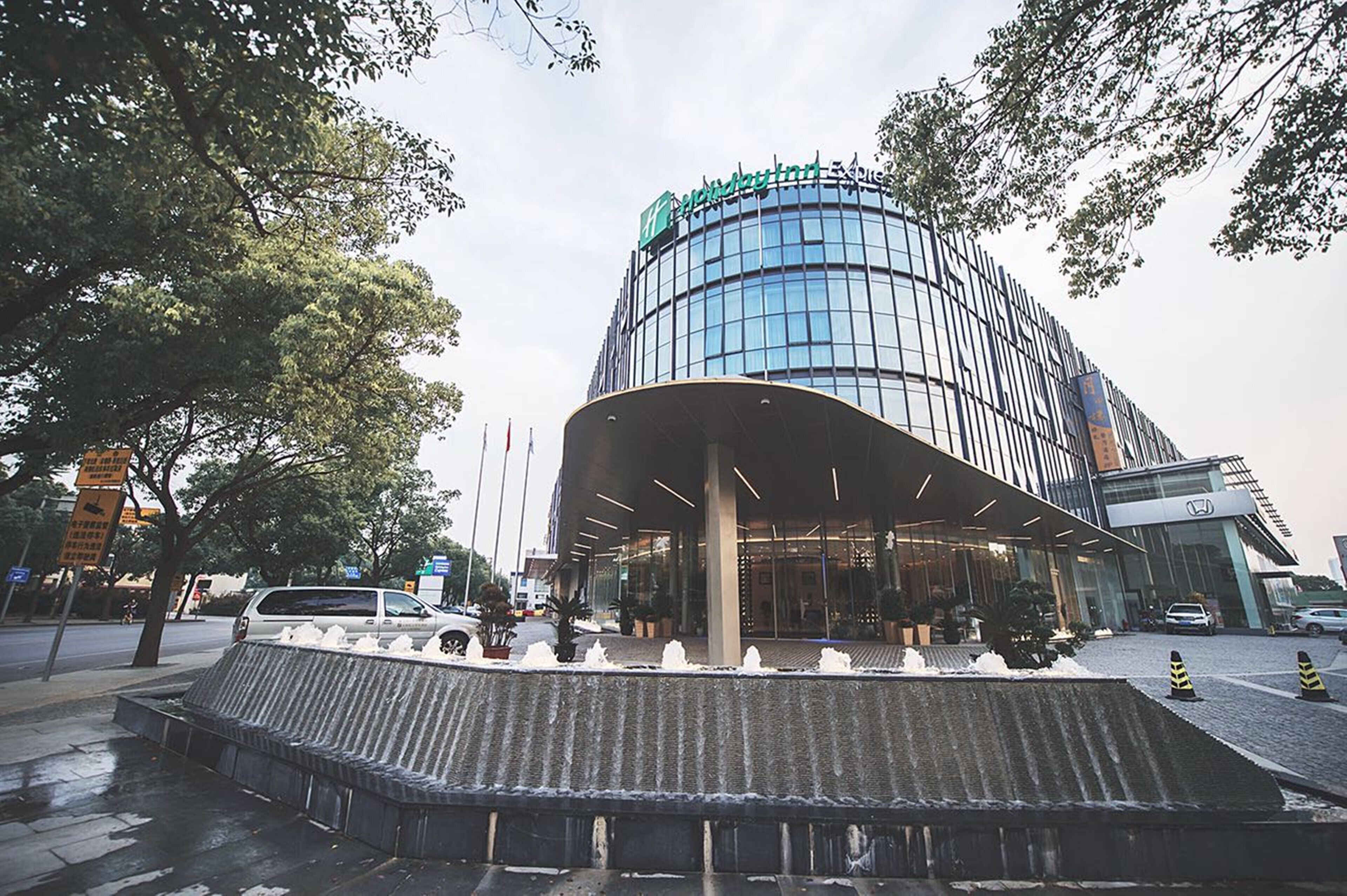 A modern hotel with a curved facade, large windows, and a covered entrance area.